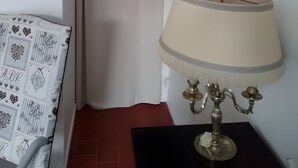 Ein Zimmer mit weißem Vorhang, einer Lampe mit beiger Lampenschirm und einem schwarzen Tisch.