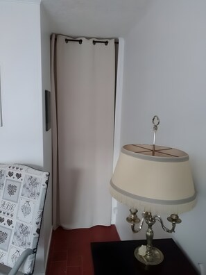 Une piĂšce avec un rideau blanc, une lampe dotĂ©e dâun abat-jour beige et une table noire.
