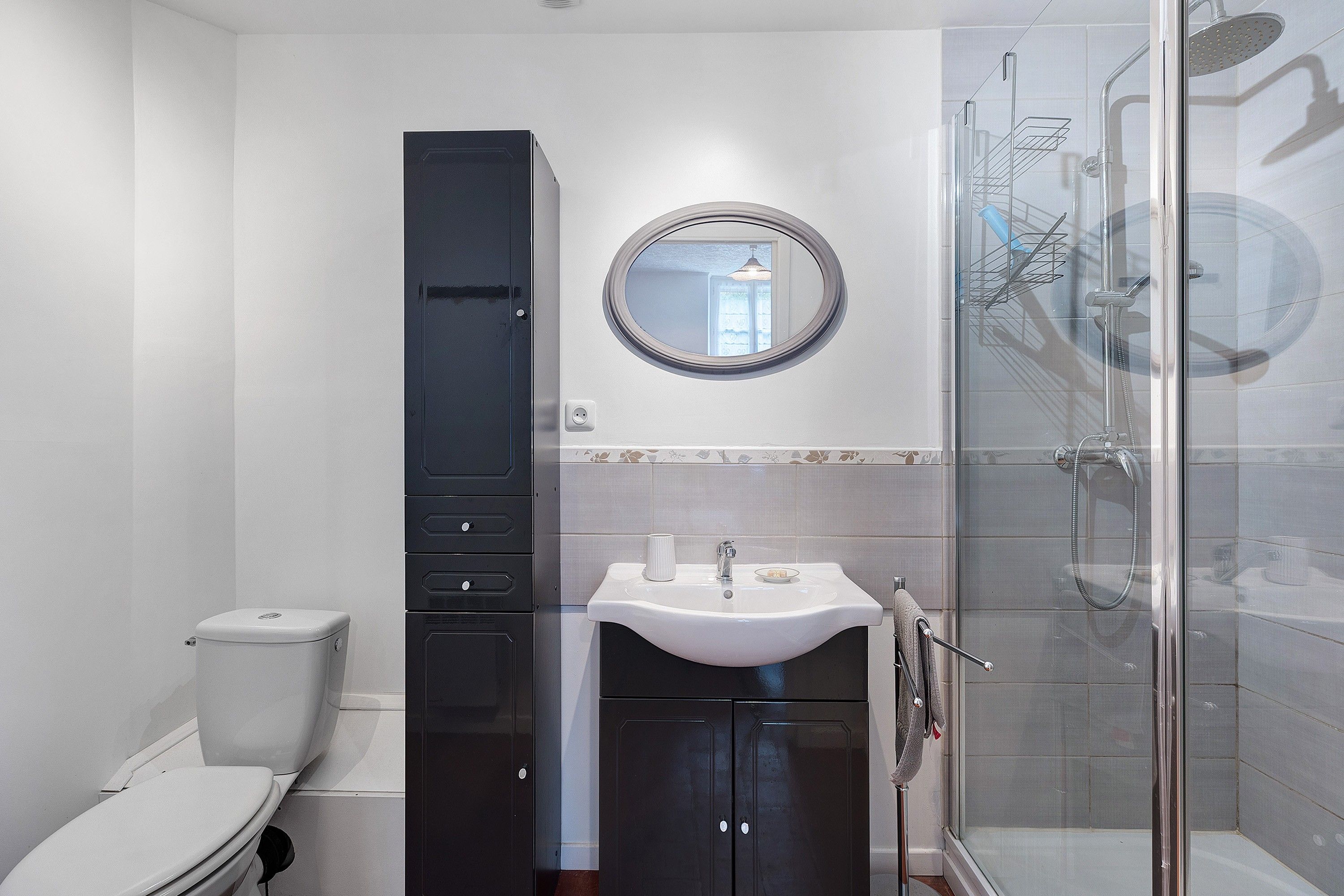 Een badkamer met toilet, wastafel, spiegel en douche.