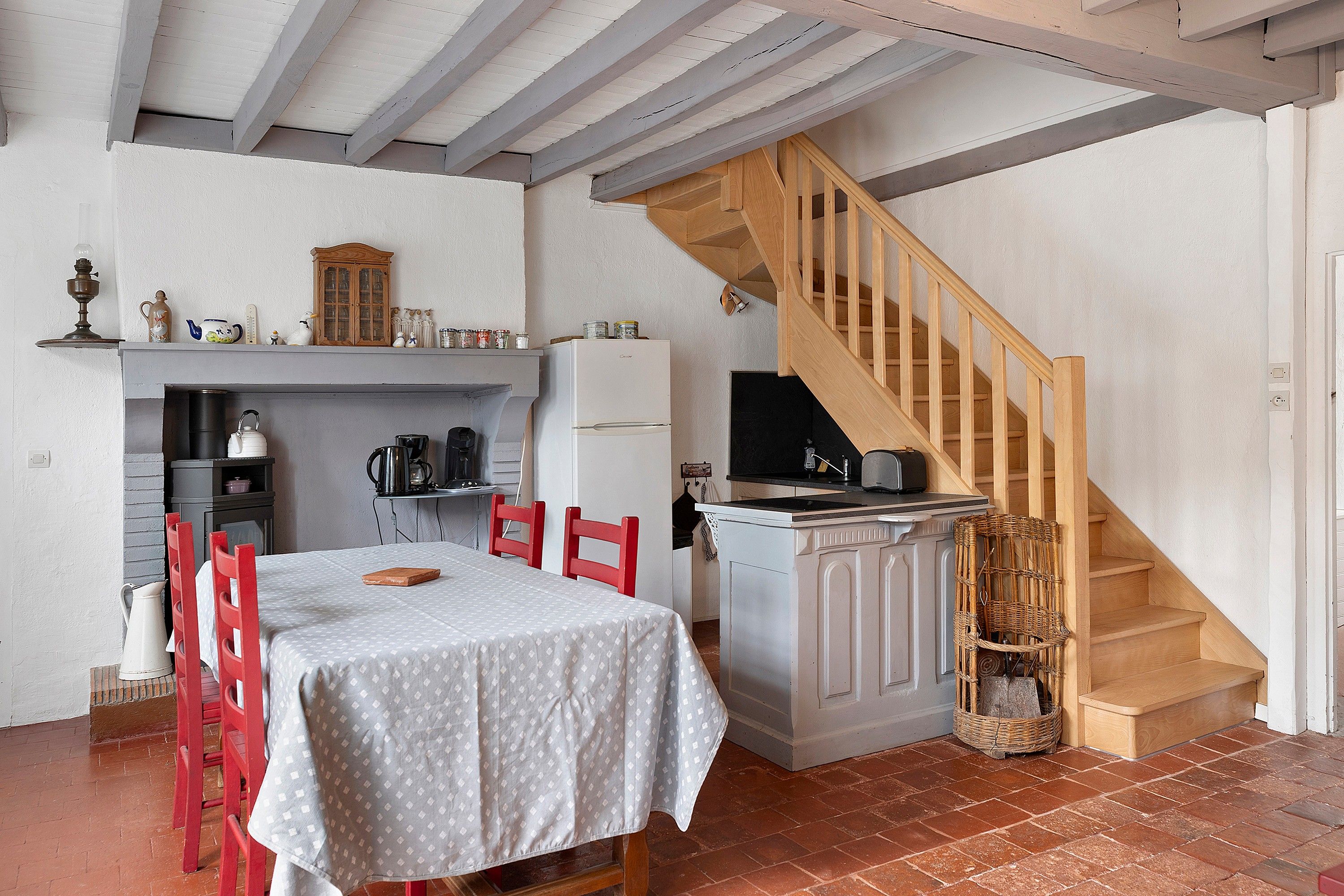 Een keuken met een eettafel, stoelen en een houten trap.