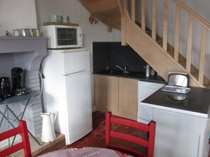 A compact kitchen with a refrigerator, microwave, and a small countertop.