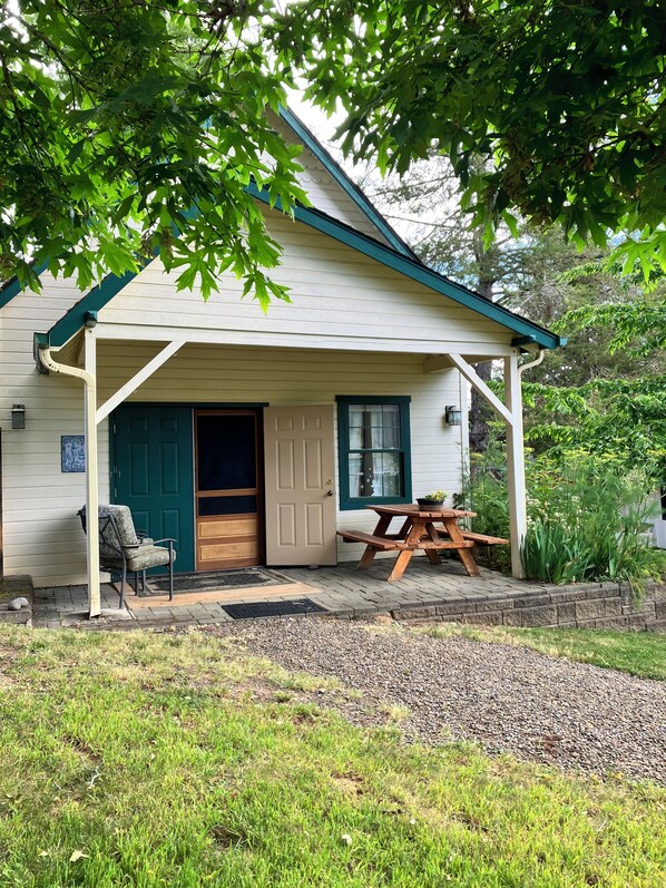 A house with a covered porch, a door, a bench, and a chair.