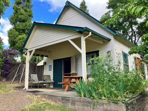 A house with a porch, a door, a window, and a garden.