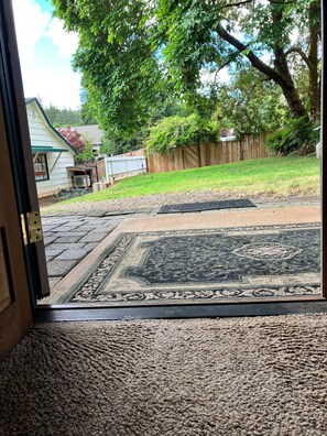 A view through a door into a backyard with a wooden deck, a grassy lawn, and a wooden fence.