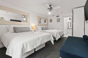 Een hotelkamer met twee bedden, een plafondventilator, een grote spiegel en een televisie.
