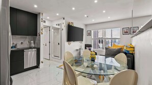 Una cocina moderna con armarios oscuros, una mesa de comedor de vidrio y un peluche de Minion sobre la mesa.