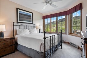 A bedroom with a bed, a ceiling fan, a window with a view of the outdoors, and a nightstand with a lamp. - Borders Lodge U308 3BD Beaver Creek Ski-in, Ski-out Condo (Avon)