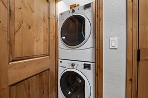 A stacked washer and dryer unit in a wooden cabinet. - Borders Lodge U308 3BD Beaver Creek Ski-in, Ski-out Condo (Avon)