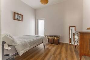Une chambre à coucher avec un lit, une commode en bois, une coiffeuse et un tableau encadré accroché au mur.