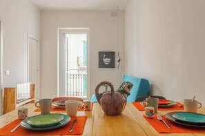 Un espace repas avec une table en bois, des chaises et une vue sur le balcon extérieur.