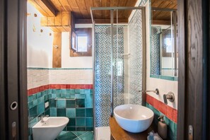 A bathroom with a white sink, a shower enclosure, and a tiled wall with geometric patterns. - Holiday Home 'Villino Rosaria Sea View' with Sea View, Wi-Fi and Air Conditioning (Dragonea)