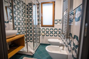 Ein Badezimmer mit Dusche, Toilette, Bidet und Waschbecken.