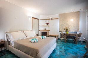 A hotel room with a bed, a desk, a chair, a fireplace, and a window with a curtain. - Holiday Home 'Villino Rosaria Sea View' with Sea View, Wi-Fi and Air Conditioning (Dragonea)