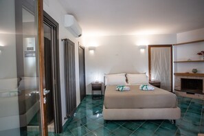Ein Hotelzimmer mit Bett, einem kleinen Tisch, einem Kamin und einem Badezimmer mit Glastür.