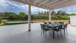 A covered patio with a dining table and chairs, a pool, and a view of the surrounding landscape. - White House Villa Luisa – Relax and Comfort Near the Beach (Santa Maria del Focallo)