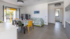 A modern kitchen with a dining area, a sofa, and a view of the outdoors. - White House Villa Luisa – Relax and Comfort Near the Beach (Santa Maria del Focallo)