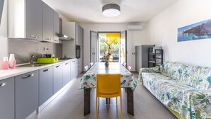 A modern kitchen with grey cabinets, a dining table, and a yellow chair. - White House Villa Luisa – Relax and Comfort Near the Beach (Santa Maria del Focallo)