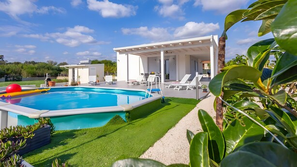 A swimming pool with a sun deck, lounge chairs, and a covered patio area. - White House Villa Luisa – Relax and Comfort Near the Beach (Santa Maria del Focallo)