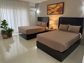 Habitación de hotel con dos camas, un ventanal con cortinas translúcidas, un cuadro en la pared y una planta en maceta.