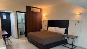 A modern bedroom with a large bed, bedside tables, a desk, and a bathroom visible through an open door. - Hotel Solé Plaza Guadalajara (Zapopan)