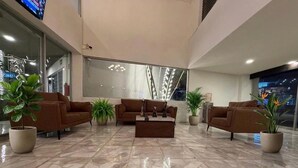 A lobby with two sofas, a coffee table, and potted plants. - Hotel Solé Plaza Guadalajara (Zapopan)