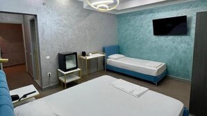 Una habitación de hotel moderna con una cama grande, un televisor montado en la pared, un escritorio pequeño y un sofá.