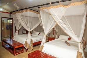 A room with two beds, each with a canopy, wooden benches, and a small table.