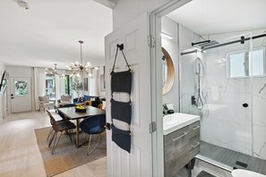Een modern interieur met een eetgedeelte, een keuken en een badkamer met een glazen douche.