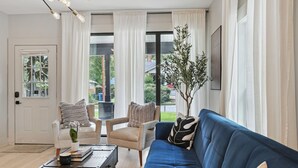Ein Wohnzimmer mit einem blauen Sofa, einer weißen Tür und Blick ins Freie.