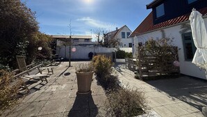 Sisäpiha, jossa on terassi, ruukkukasveja ja ulkokalusteita.