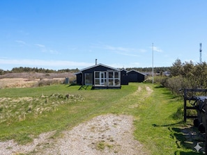 A single-story building with a large window, a gravel path leading to it, and a wooden fence in the foreground. - 4 Star Holiday Home in Allinge (Allinge)