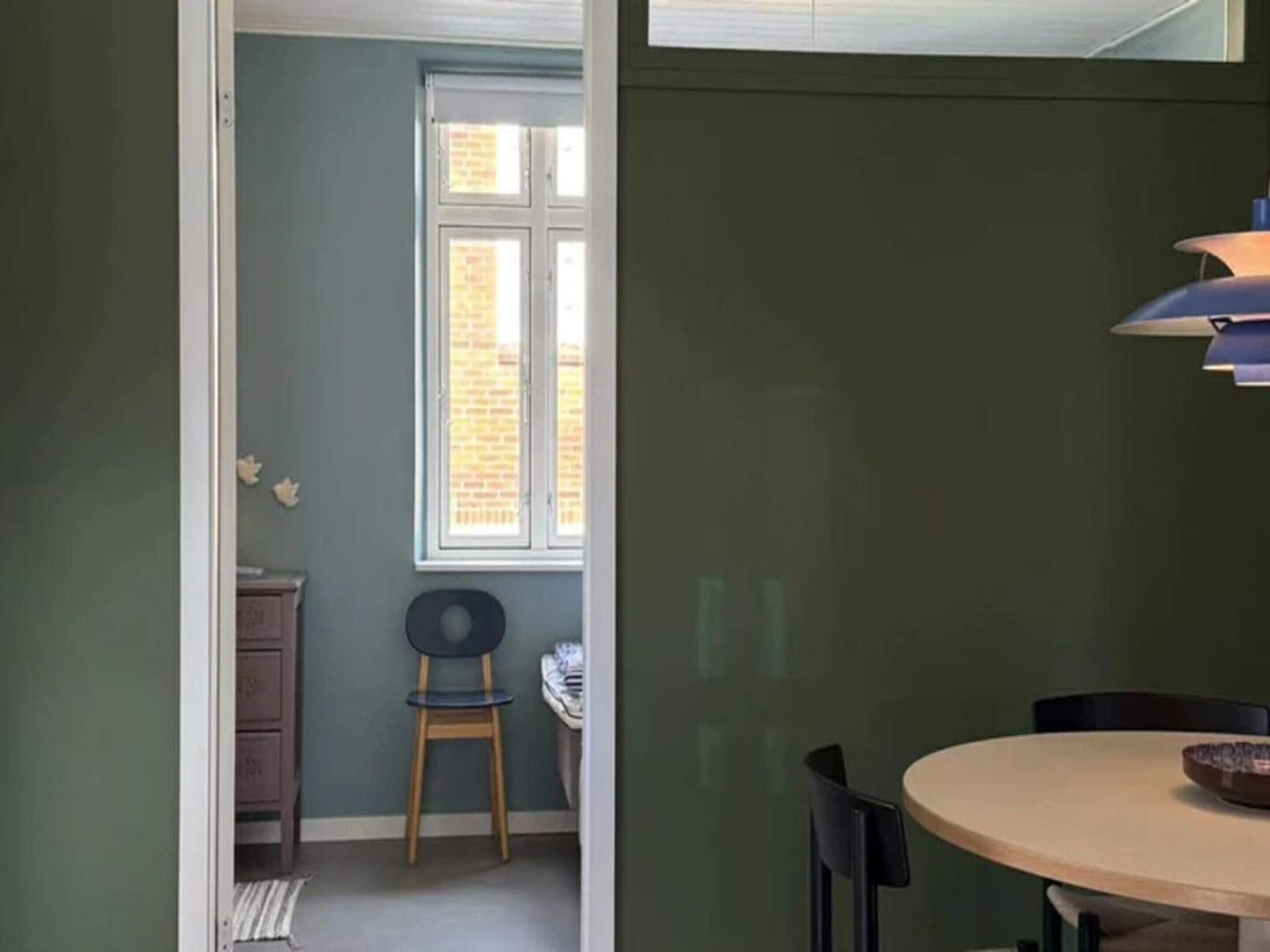 A room with a round table, a chair, a window, and a door.