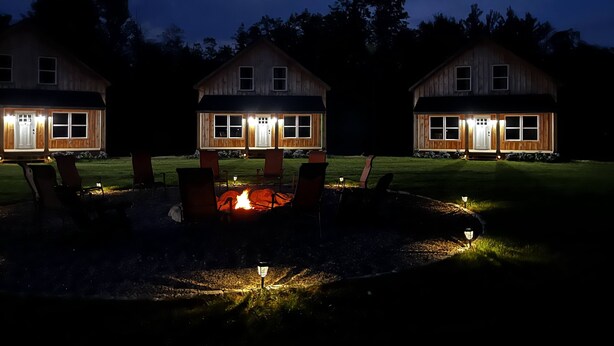 Three wooden cabins with a central fire pit, surrounded by chairs and a well-lit lawn. - The Cabins at Timber Ridge - 6 Cabin Group Retreat - Weddings, Reunions, Clubs (Tamworth)