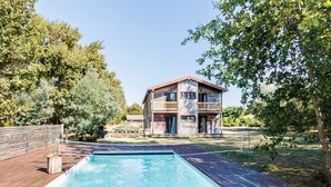 Una casa a due piani in legno con una piscina di fronte.