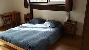 Un dormitorio con cama, escritorio, silla y mesita de noche.