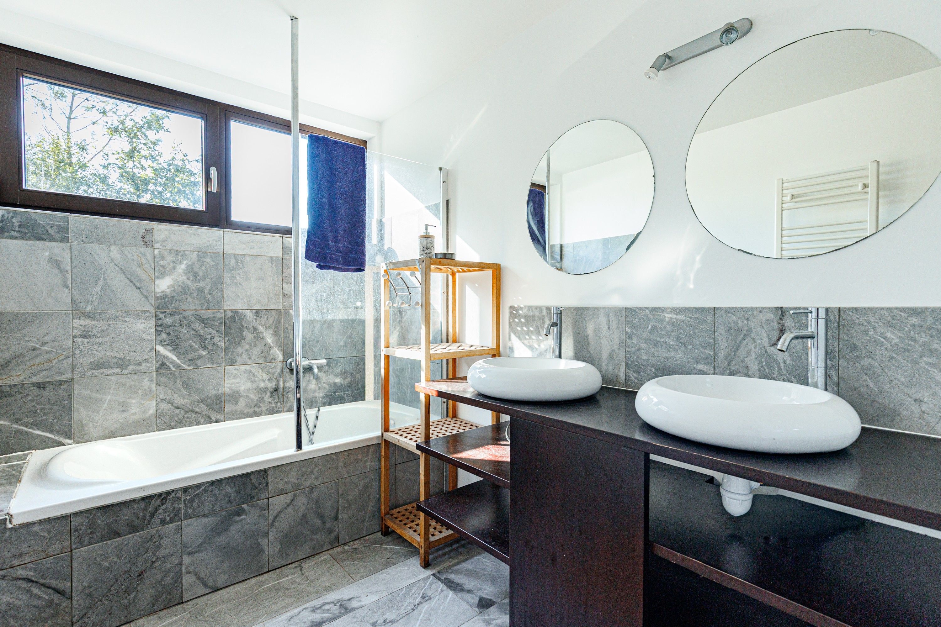 Een moderne badkamer met een bad, twee wasbakken, een douche en een grote spiegel.