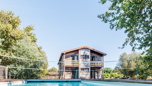 Un edificio in legno a due piani con una piscina di fronte.
