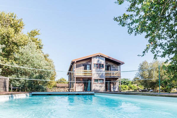 A two-story wooden building with a swimming pool in front.