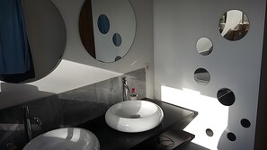 A modern bathroom with a round sink, a mirror, and a wall with circular cutouts. - Holiday Home “Villa Pura Vida” with Private Pool, Terrace and Wi-Fi (Lit-et-Mixe)
