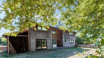 Une maison moderne à deux étages, dotée d’un grand garage ouvert et d’un espace extérieur abrité.