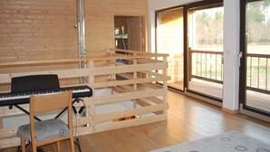 Une pièce avec un mur en bois, un piano, une chaise et une grande porte-fenêtre coulissante donnant sur un espace extérieur.