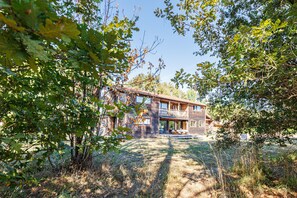 A wooden cabin with a balcony, surrounded by trees and a clear sky.