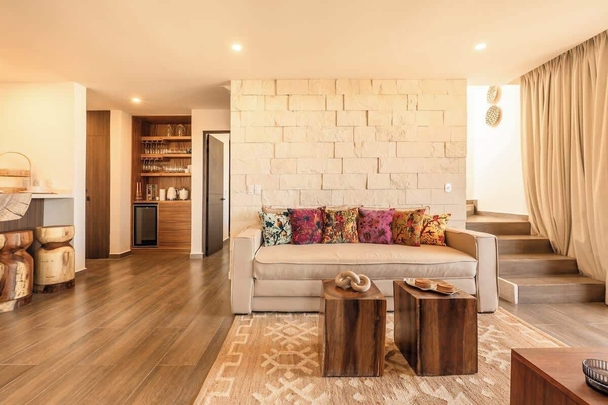 A living room with a sofa, wooden coffee table, and a stone wall.