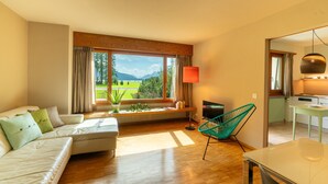 Ein modernes Wohnzimmer mit Sofa, Fernseher, Tisch und Stuhl.