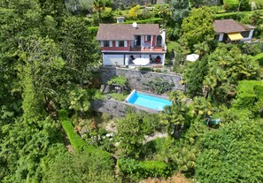 Ein zweistöckiges Haus mit Schwimmbad, umgeben von üppiger Vegetation.