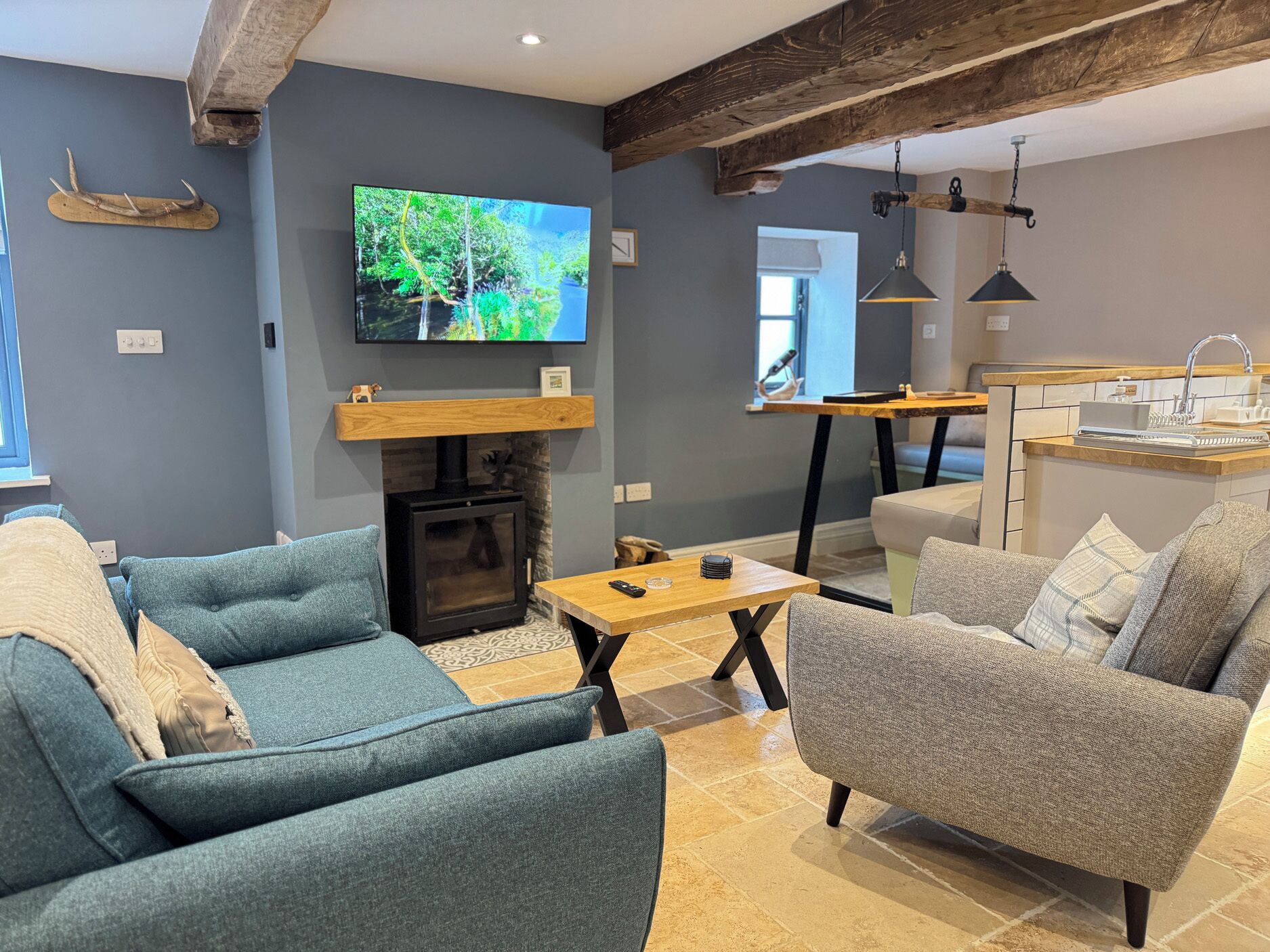 Una sala de estar con dos sofás, chimenea, televisión y una zona de cocina.