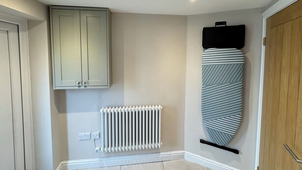 A room with a radiator, a cabinet, and a surfboard on the wall. - Railway Cottage (Oswestry)