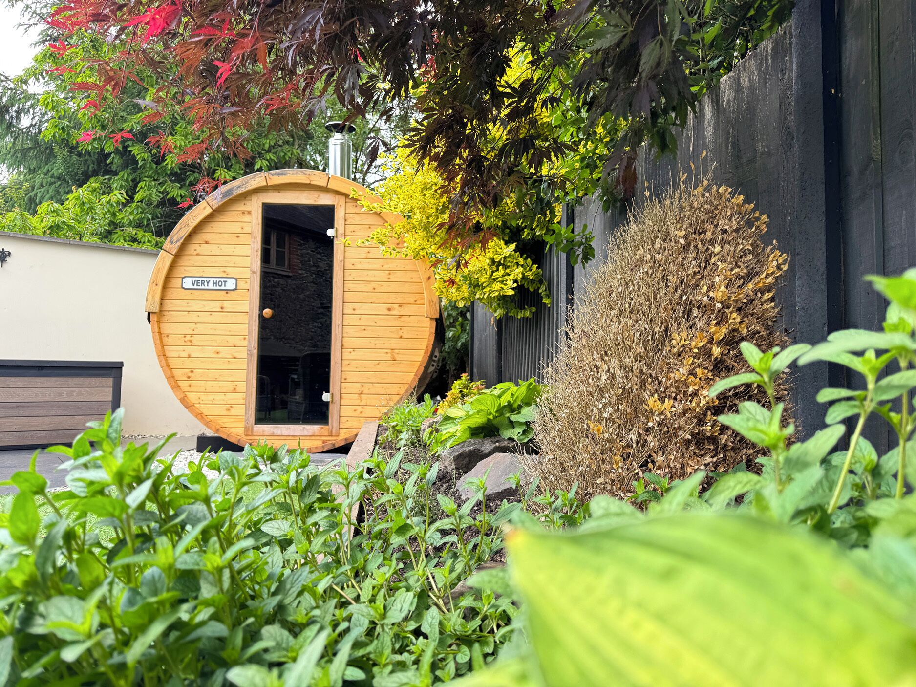 A wooden sauna structure with a sign reading 'VERY HOT' and a door.