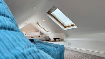Un dormitorio con techo inclinado, tragaluces y cama con cabecera.