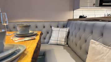 Una cocina moderna con una mesa de comedor de madera, un banco tapizado gris y un microondas encima.